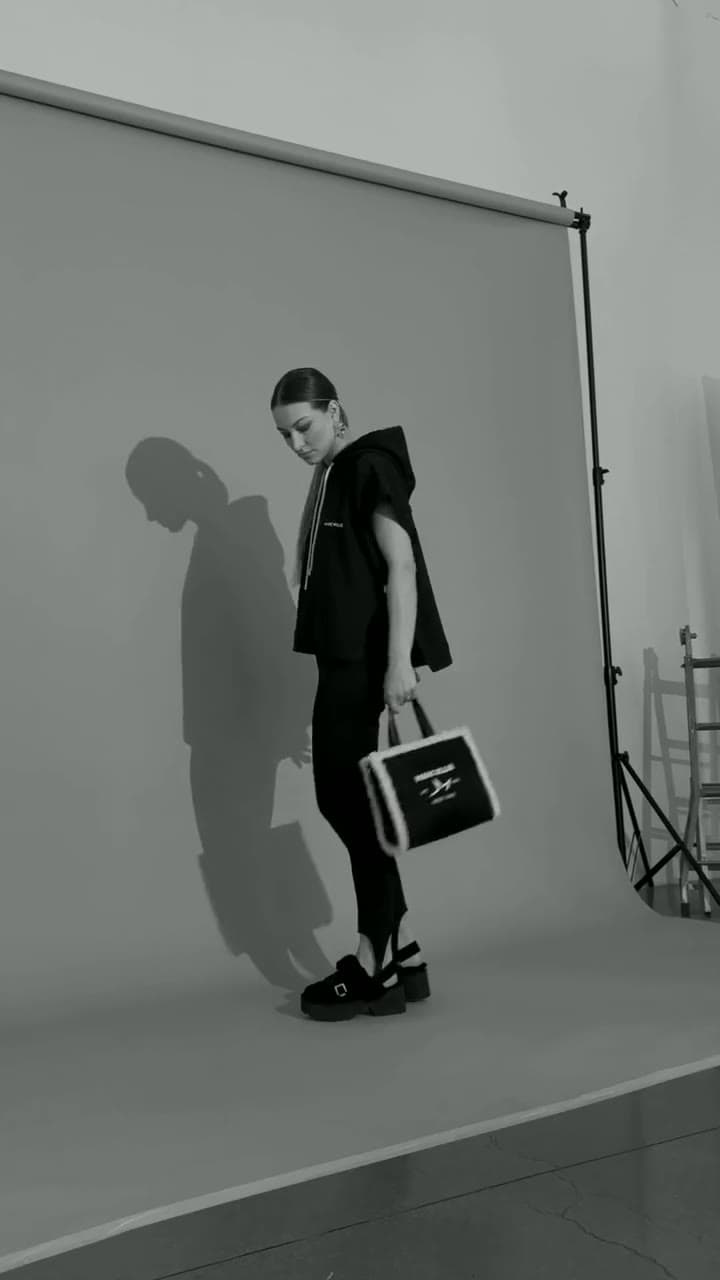 Marc Ellis — backstage dello shooting FW26-27: modella con borsa sul fondale grigio