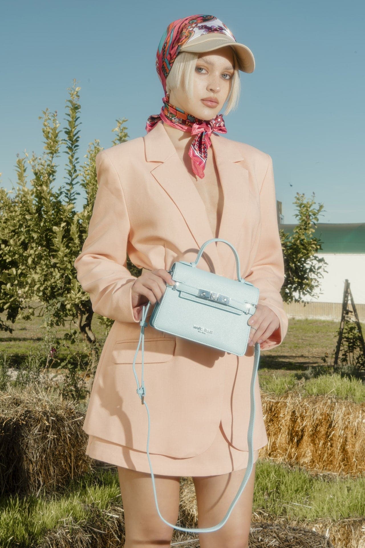 Marc Ellis — modella in blazer rosa con borsa azzurra