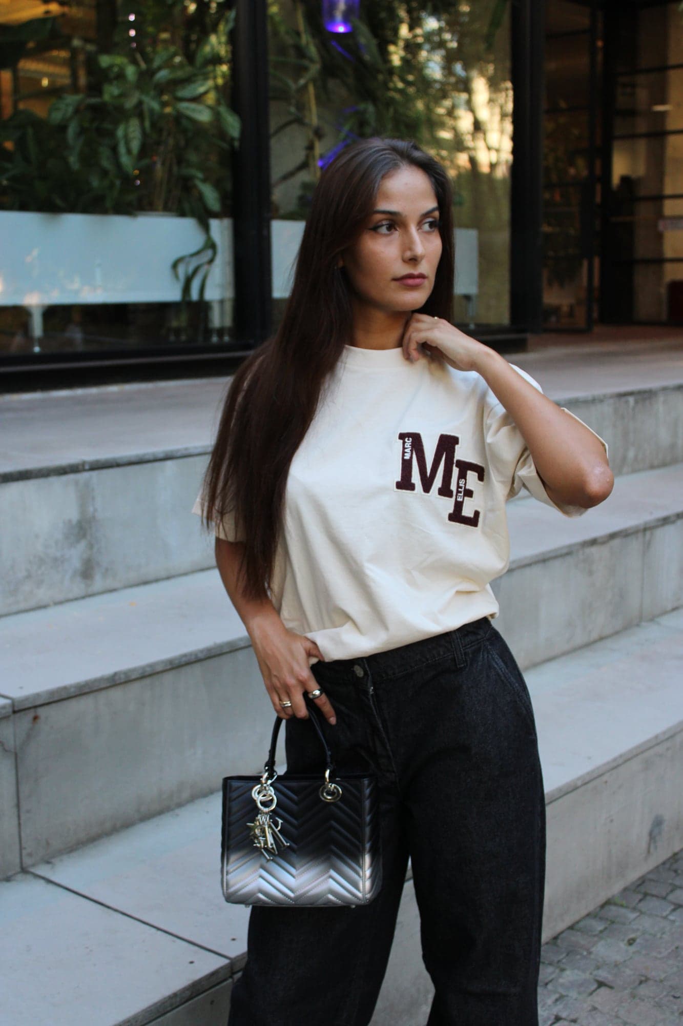 Marc Ellis — modella in t-shirt bianca con logo e borsa nera