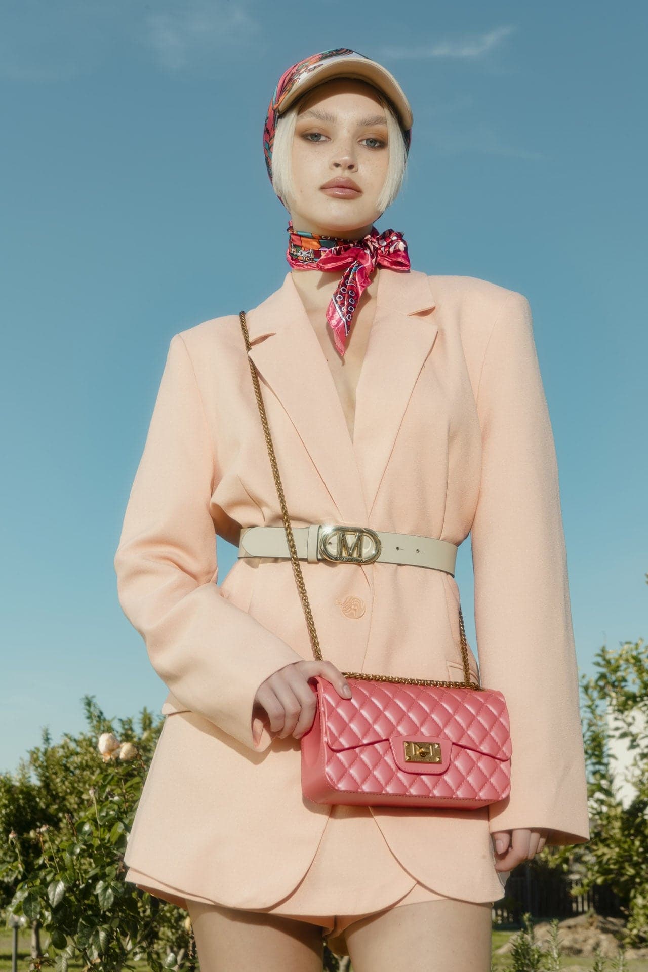 Marc Ellis — modella in blazer rosa con borsa trapuntata rossa a tracolla