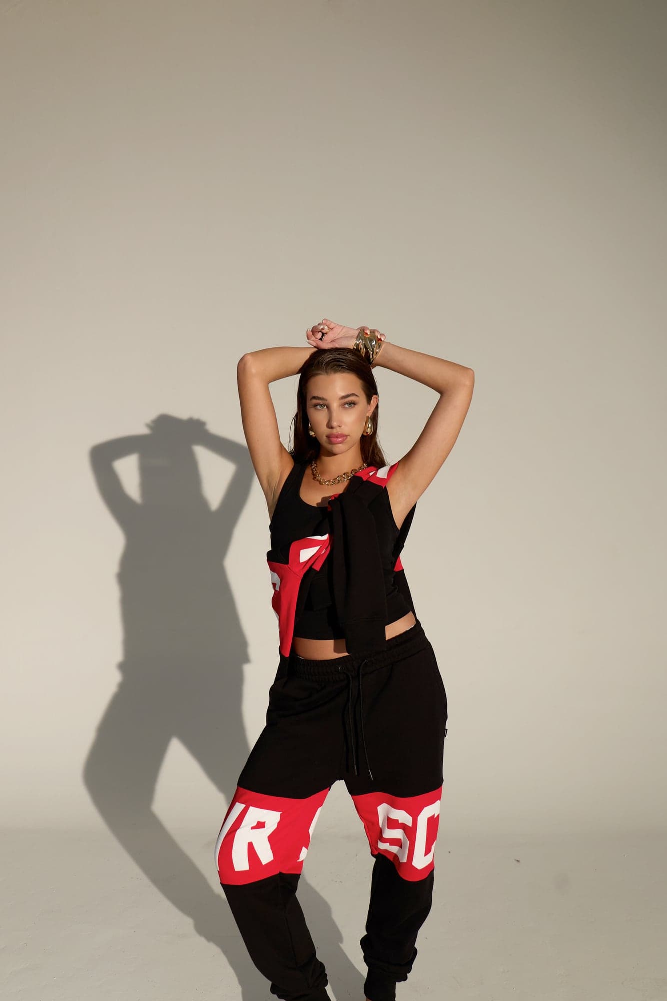 VRSC Couture — modella in completo nero e rosso con logo VRSC, braccia alzate