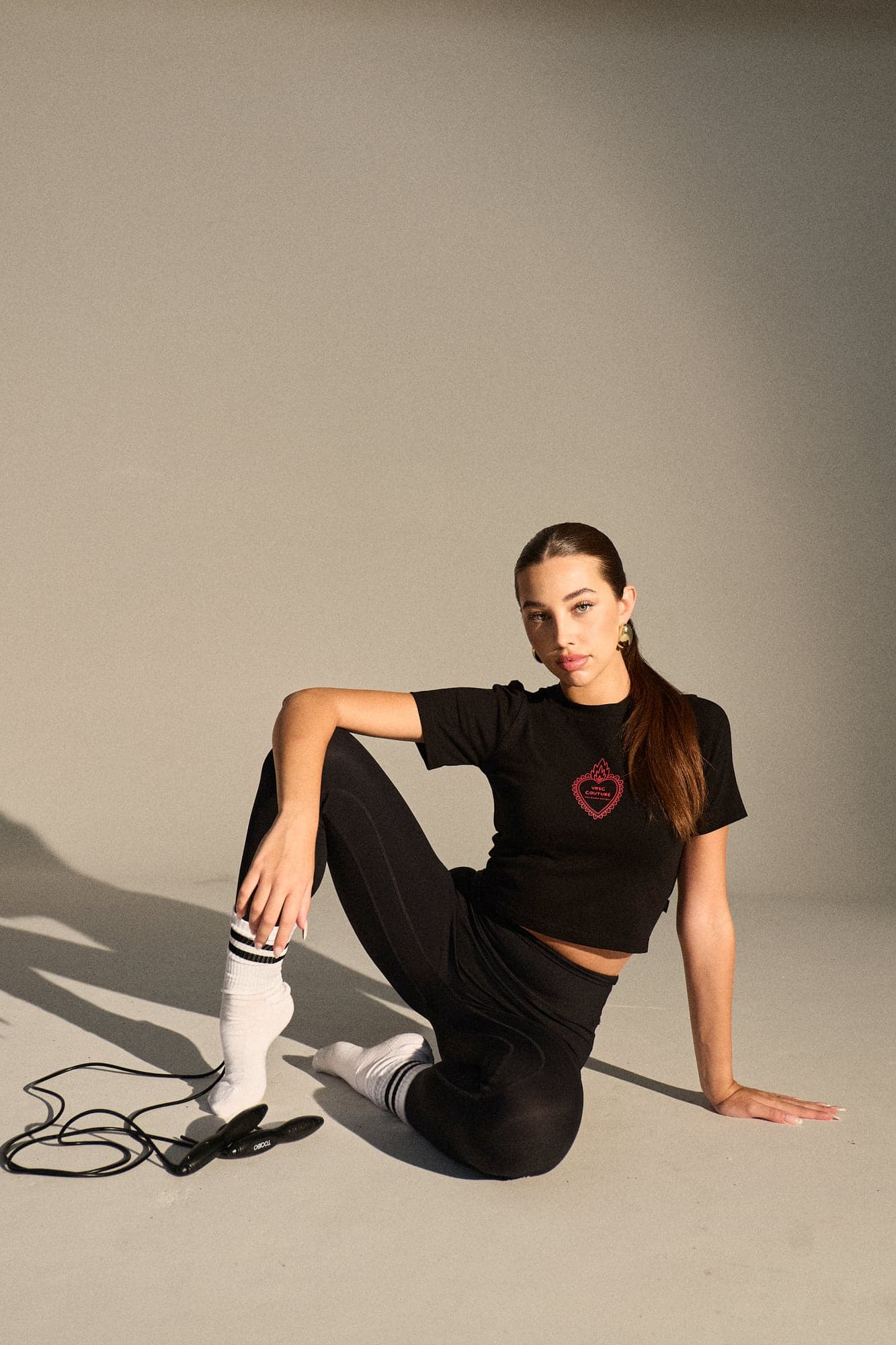 VRSC Couture — modella seduta a terra in t-shirt nera con cuore VRSC Couture
