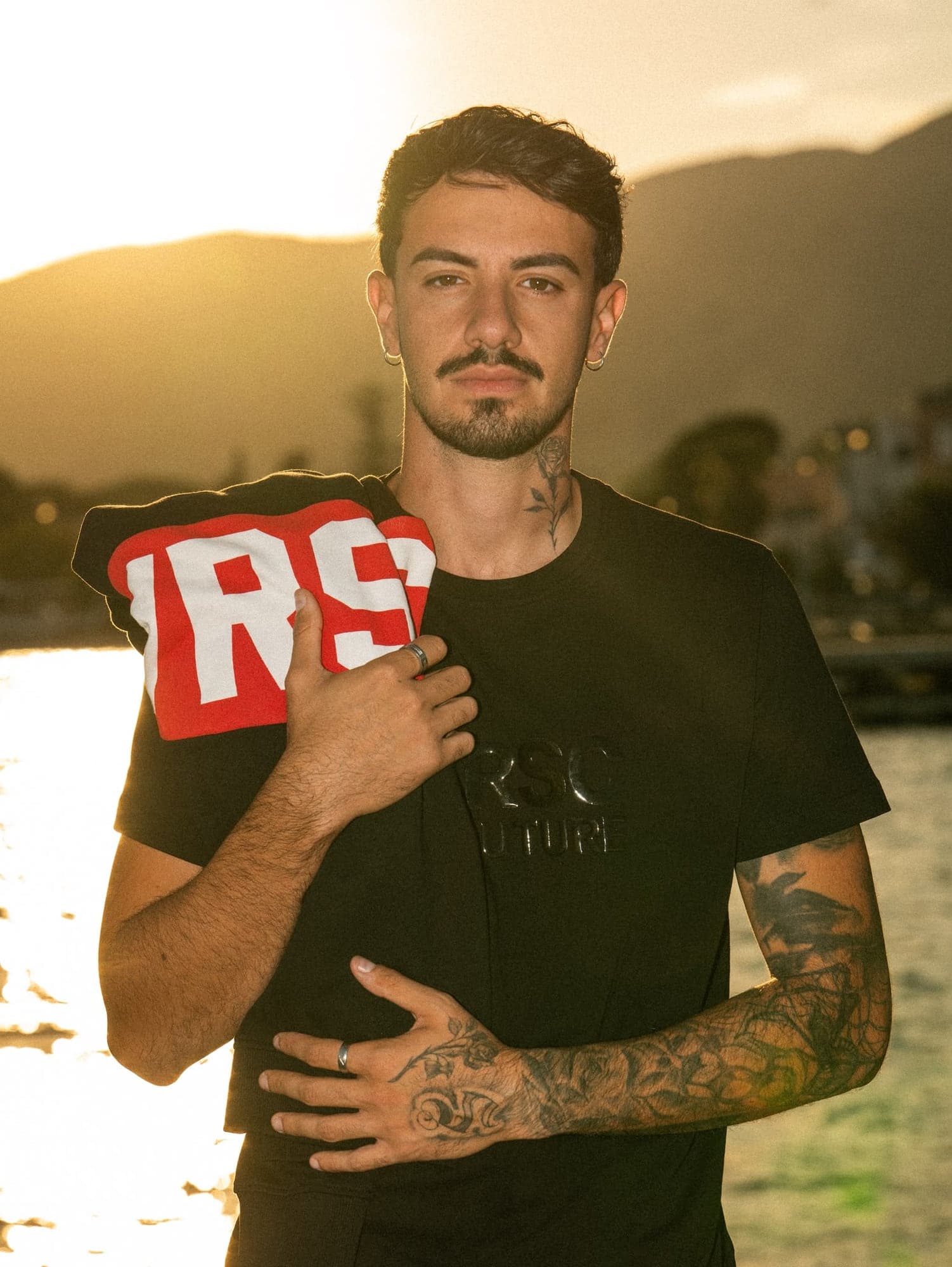 VRSC Couture — modello in t-shirt nera VRSC al tramonto con felpa rossa in spalla